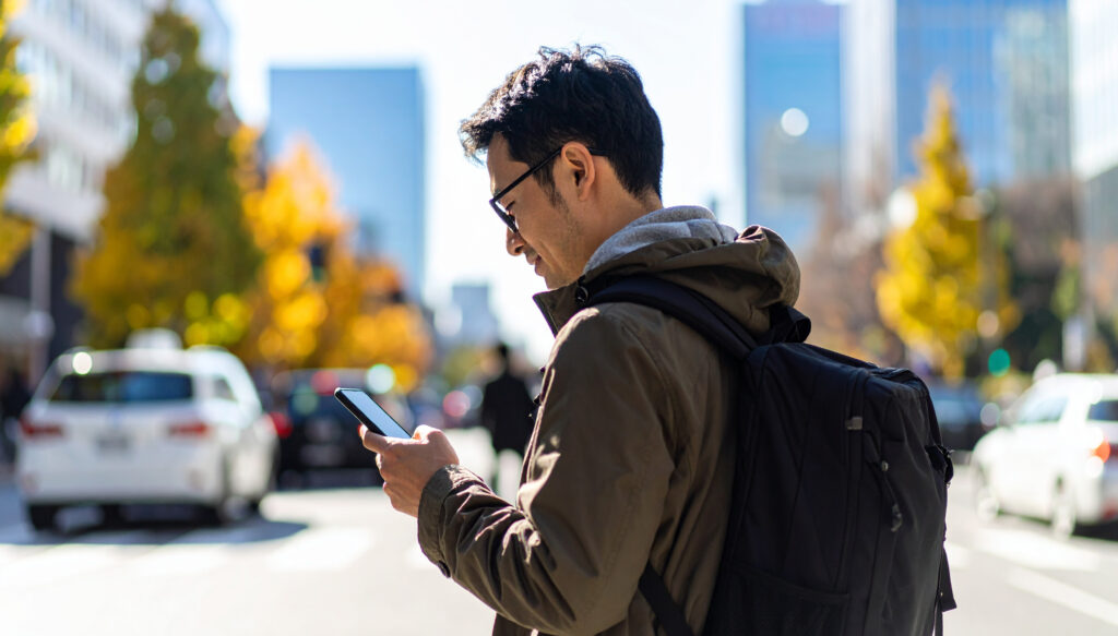 スマートフォンを見る男性、街中、道路