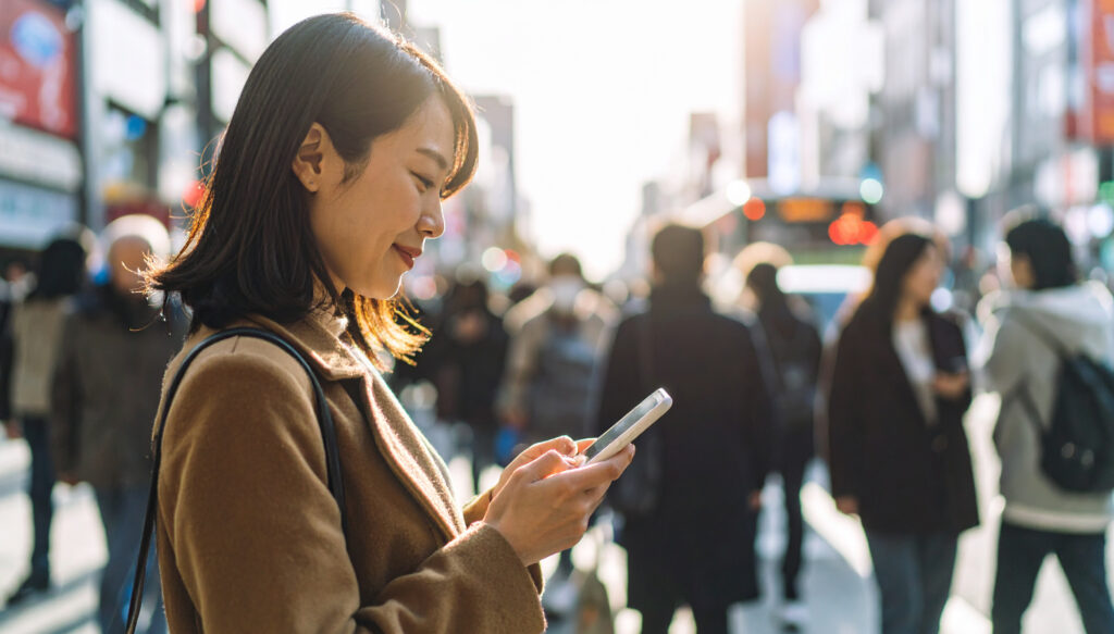 スマートフォンを見る女性、街の雑踏