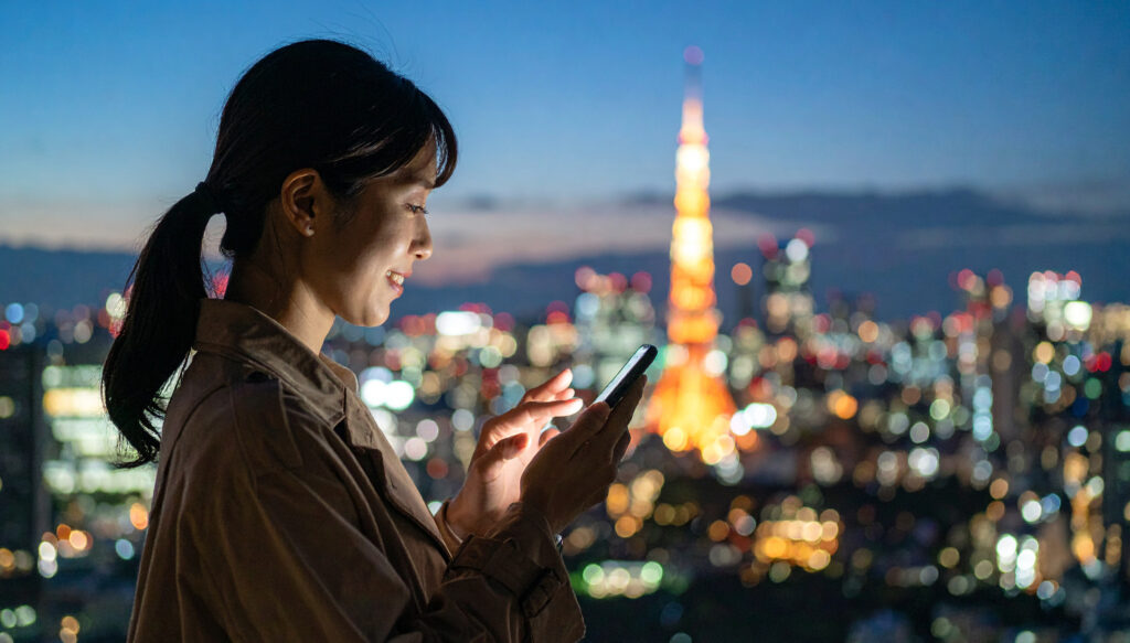スマートフォンを見る女性、東京タワー夜景